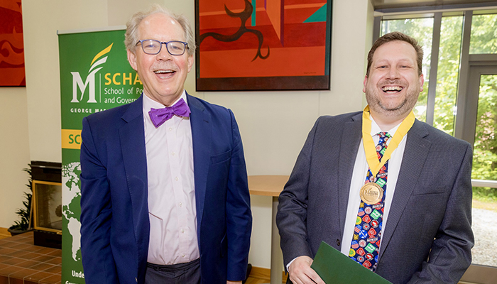 Two men in suit jackets laugh at the camera.