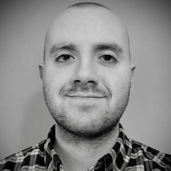 A young man in a black and white portrait smiles serenely at the camera.