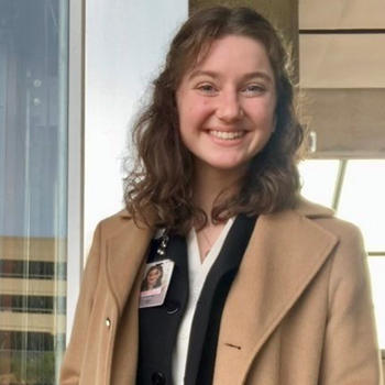 A young woman with a Congressional badge smiles at the camera.