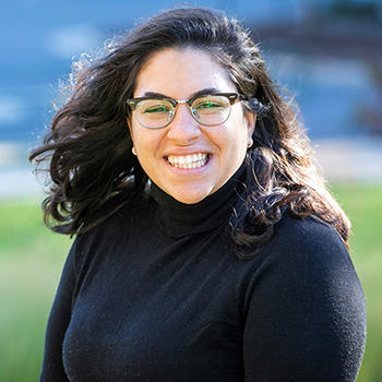 A young woman in glasses smiles at the camera.