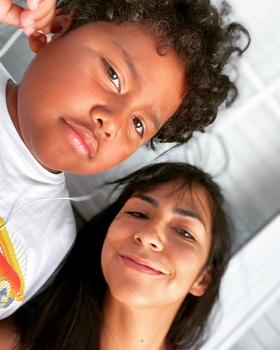 A boy with curly dark hair and a woman with dark hair gaze at the camera.